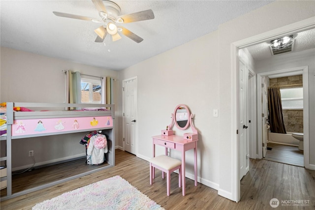 bedroom featuring a textured ceiling, wood finished floors, a ceiling fan, visible vents, and baseboards