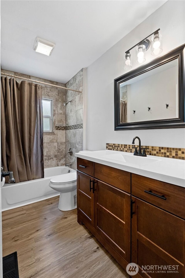 bathroom featuring shower / tub combo, tasteful backsplash, toilet, wood finished floors, and vanity