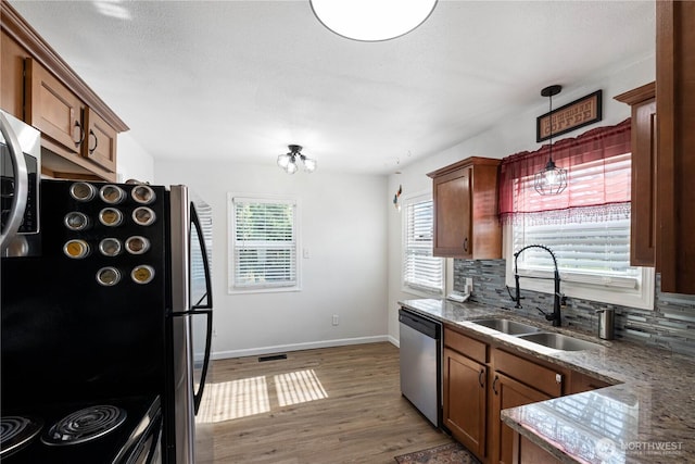 kitchen featuring tasteful backsplash, a sink, wood finished floors, dishwasher, and baseboards