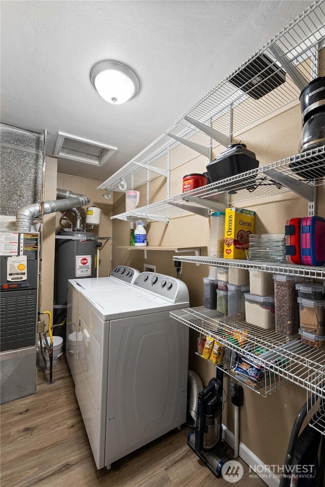 laundry area featuring electric water heater, laundry area, wood finished floors, independent washer and dryer, and attic access