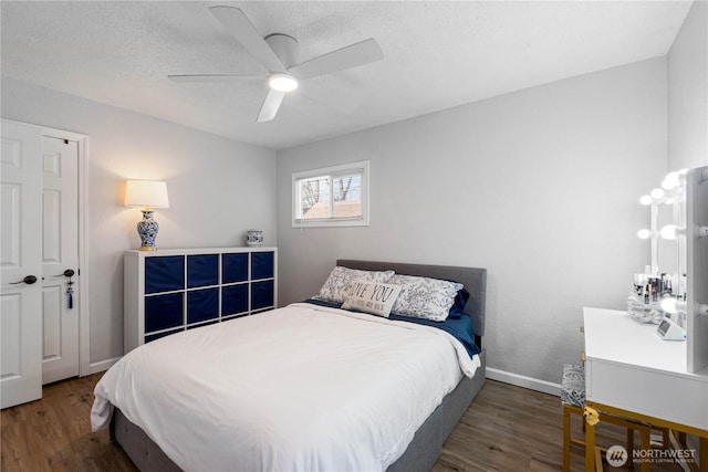 bedroom featuring a ceiling fan, a textured ceiling, baseboards, and wood finished floors