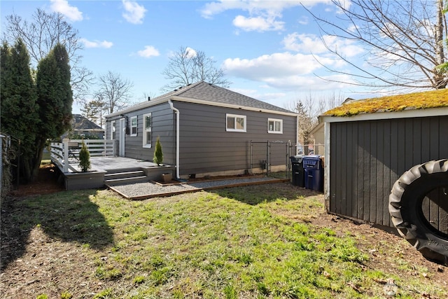 rear view of house with a yard, fence, a deck, a shed, and an outdoor structure