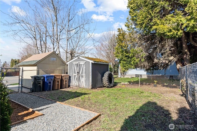 view of yard featuring a storage shed, a gate, fence, and an outbuilding