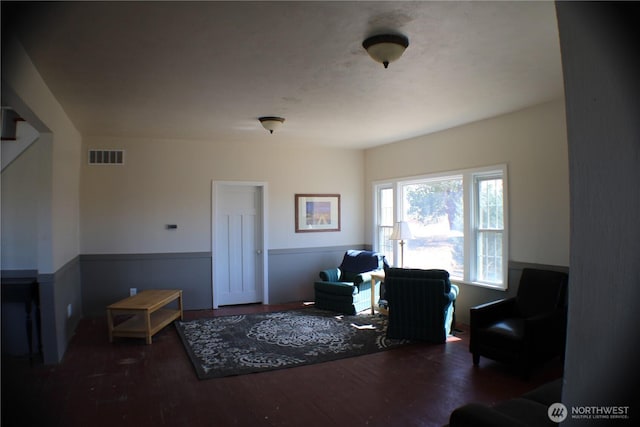 living area with wood finished floors, visible vents, and wainscoting