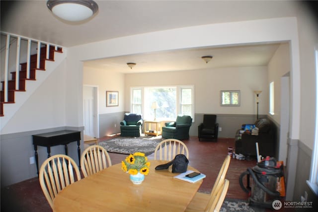 dining area featuring stairway, wood finished floors, and wainscoting