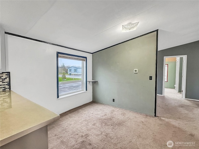 carpeted empty room featuring vaulted ceiling