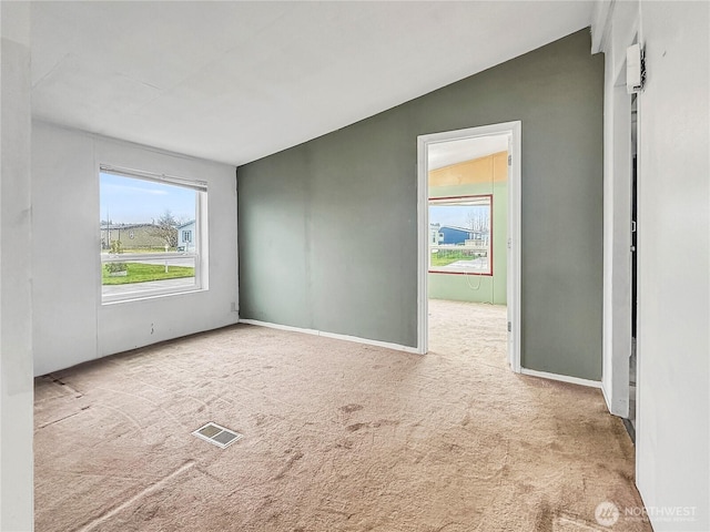 spare room with visible vents, baseboards, carpet, and vaulted ceiling