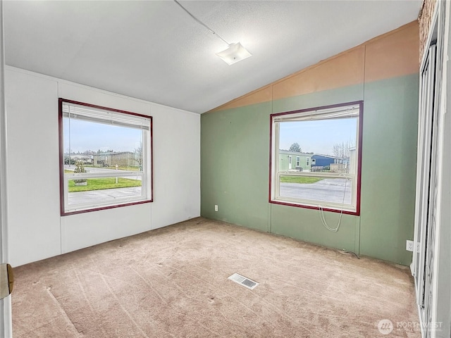 unfurnished room with visible vents, lofted ceiling, and carpet flooring