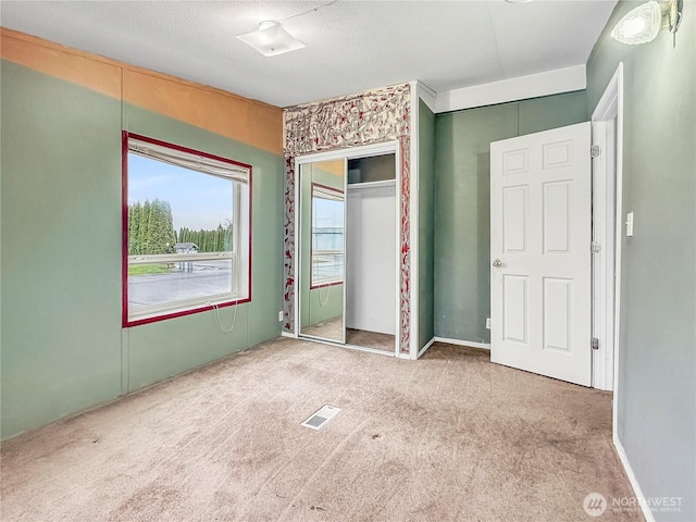 unfurnished bedroom featuring carpet flooring, visible vents, and a closet