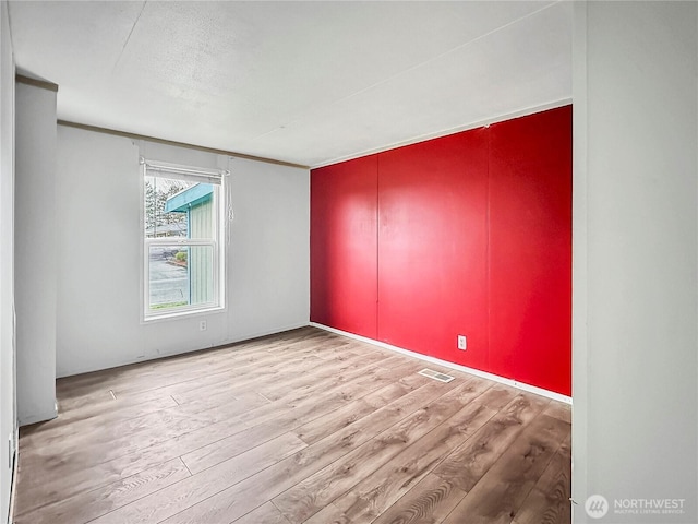 spare room featuring visible vents and wood finished floors