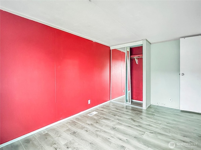 unfurnished bedroom with visible vents, a closet, and wood finished floors