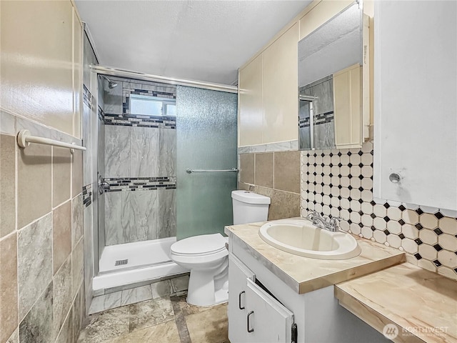 full bathroom with toilet, tile walls, a stall shower, and vanity