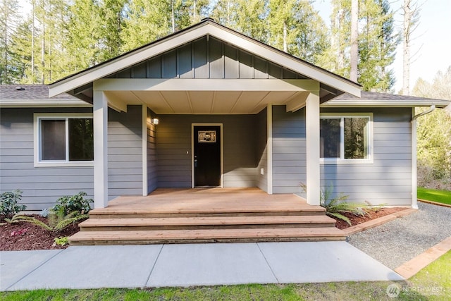 property entrance featuring a carport, covered porch, board and batten siding, and roof with shingles