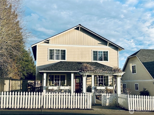 view of front of property featuring a fenced front yard, a porch, and a shingled roof