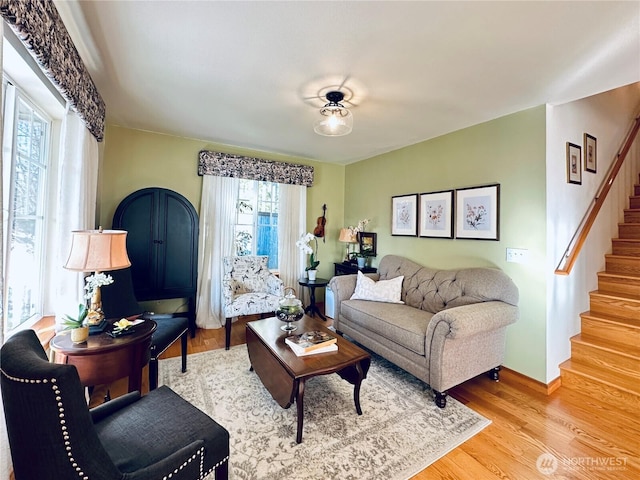 living area featuring baseboards, wood finished floors, and stairs