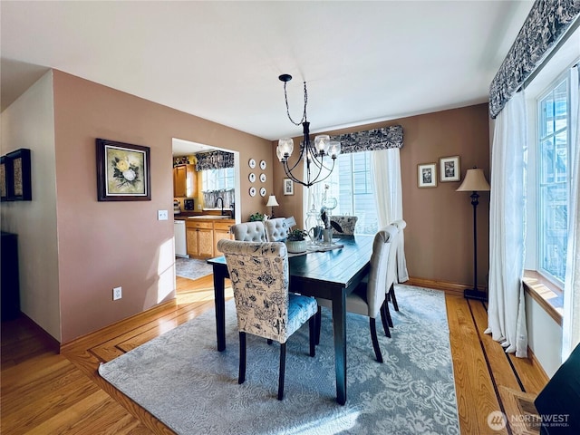 dining space with a notable chandelier, plenty of natural light, and light wood-type flooring