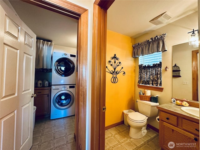 bathroom featuring stacked washer / dryer, visible vents, toilet, tile patterned floors, and vanity