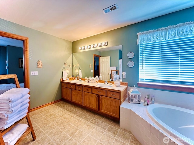 bathroom with baseboards, visible vents, double vanity, a sink, and a bath