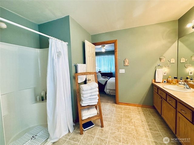 ensuite bathroom featuring vanity, ensuite bath, a shower with curtain, and baseboards