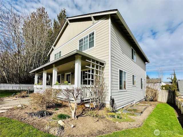 view of side of property featuring a porch and fence