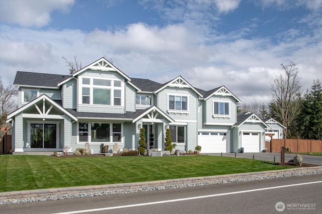 view of front of house featuring a garage, driveway, a front lawn, and fence