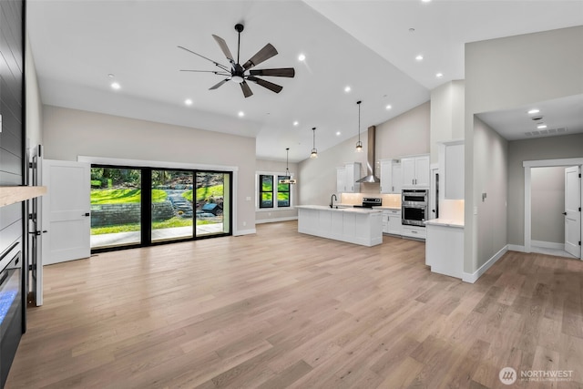 kitchen featuring light countertops, light wood-style flooring, open floor plan, and high vaulted ceiling