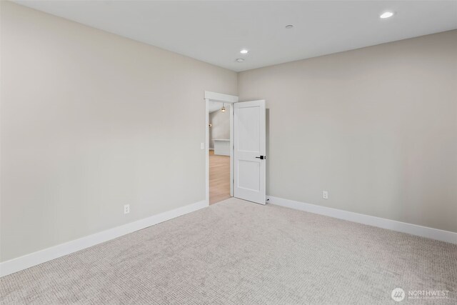 spare room with recessed lighting, light colored carpet, and baseboards