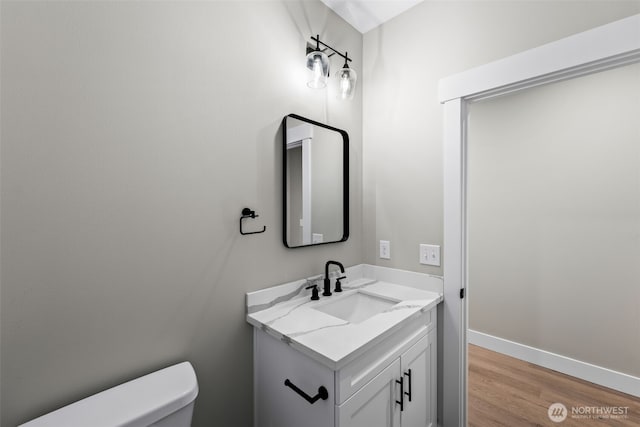 bathroom featuring toilet, vanity, baseboards, and wood finished floors