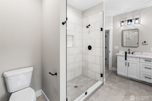 bathroom with a stall shower, toilet, vanity, and baseboards