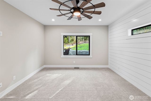 carpeted empty room featuring recessed lighting, baseboards, ceiling fan, and wood walls