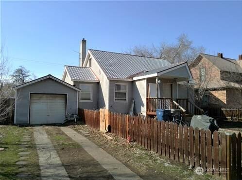 view of front of home featuring a chimney, concrete driveway, fence, metal roof, and a garage