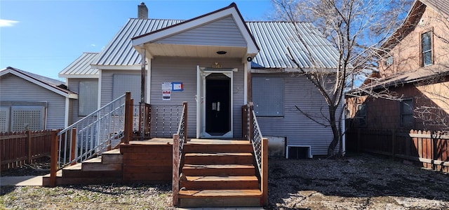 view of front of home featuring metal roof, a chimney, and fence