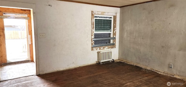 spare room with radiator, crown molding, and wood-type flooring