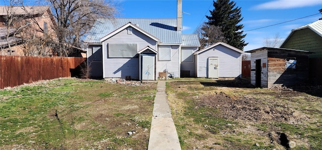 exterior space with a shed, fence, metal roof, and an outbuilding