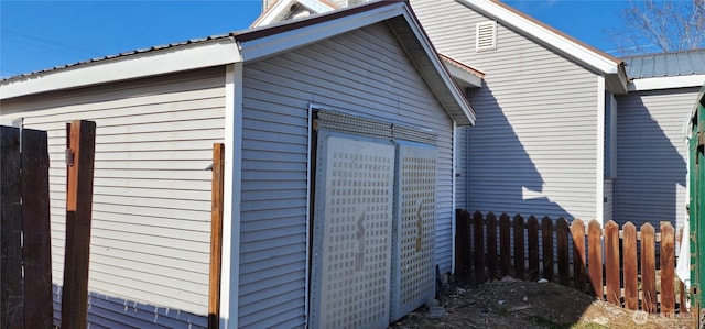 view of property exterior featuring fence, metal roof, and an outdoor structure