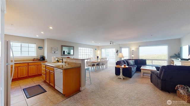 kitchen featuring a breakfast bar, an island with sink, a sink, dishwasher, and open floor plan