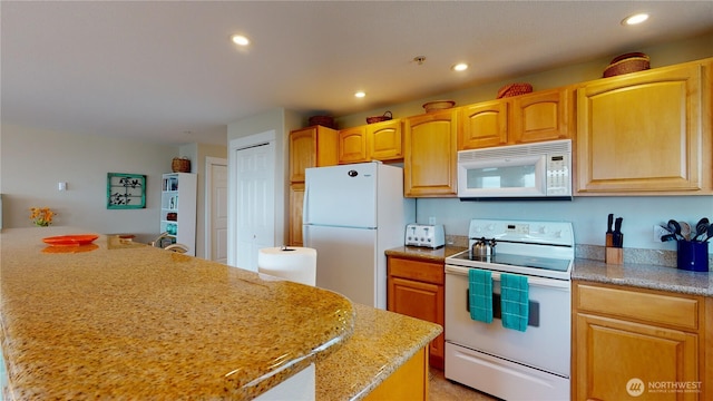 kitchen featuring white appliances, light stone counters, and recessed lighting