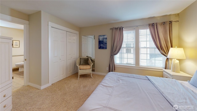 carpeted bedroom featuring ensuite bath and baseboards