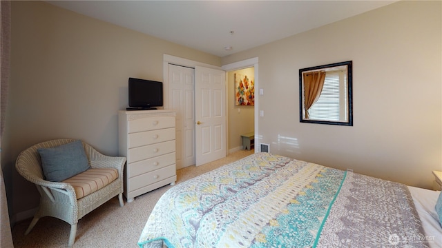 bedroom with visible vents, a closet, and light carpet