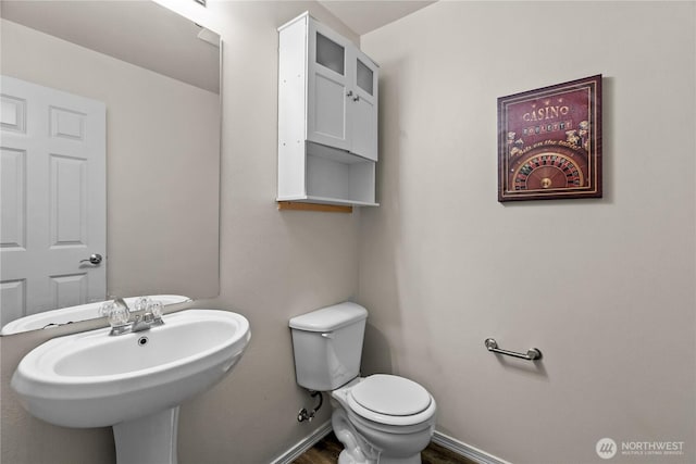 half bath featuring a sink, toilet, and baseboards