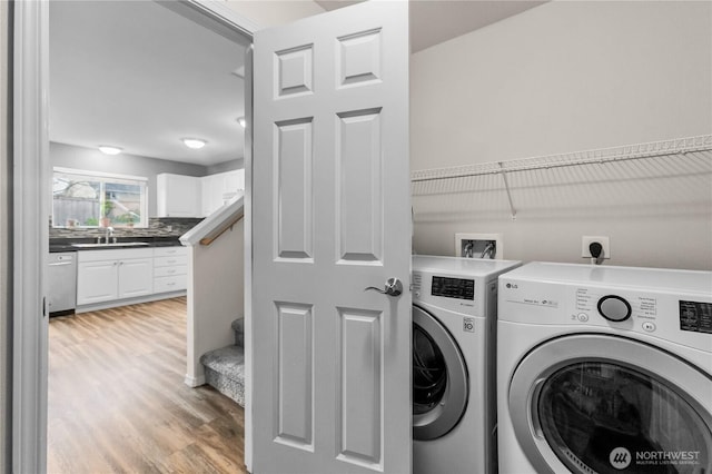 laundry room with a sink, laundry area, light wood finished floors, and washing machine and dryer