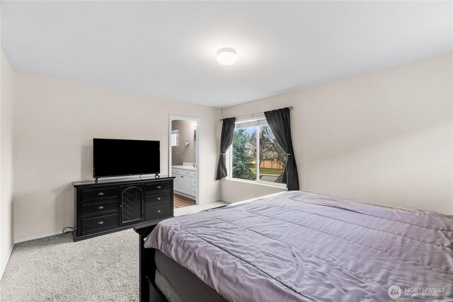 bedroom with light carpet, baseboards, and ensuite bathroom