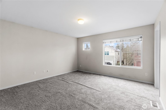 unfurnished room with carpet floors, visible vents, and baseboards