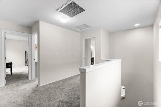 hallway with attic access, baseboards, visible vents, and carpet flooring