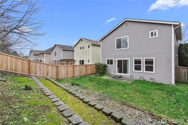 rear view of property with entry steps, a fenced backyard, and a lawn