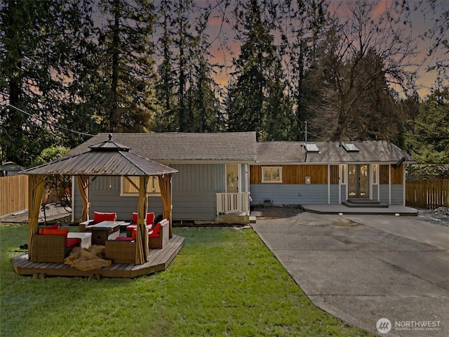 view of front of house featuring a gazebo, fence, french doors, outdoor lounge area, and a front yard