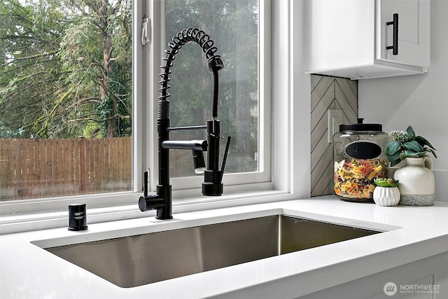 interior details featuring light countertops, a sink, and white cabinets