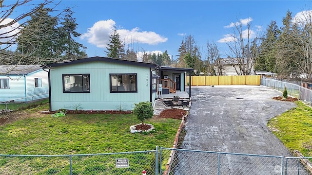 view of front of home with a fenced front yard, driveway, and a front lawn