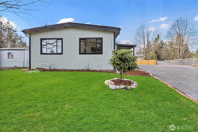 view of side of home featuring aphalt driveway, crawl space, fence, and a lawn