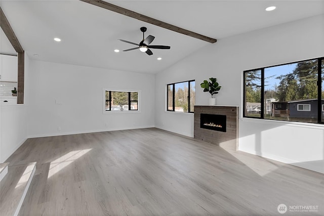 unfurnished living room with vaulted ceiling with beams, a tiled fireplace, wood finished floors, and recessed lighting